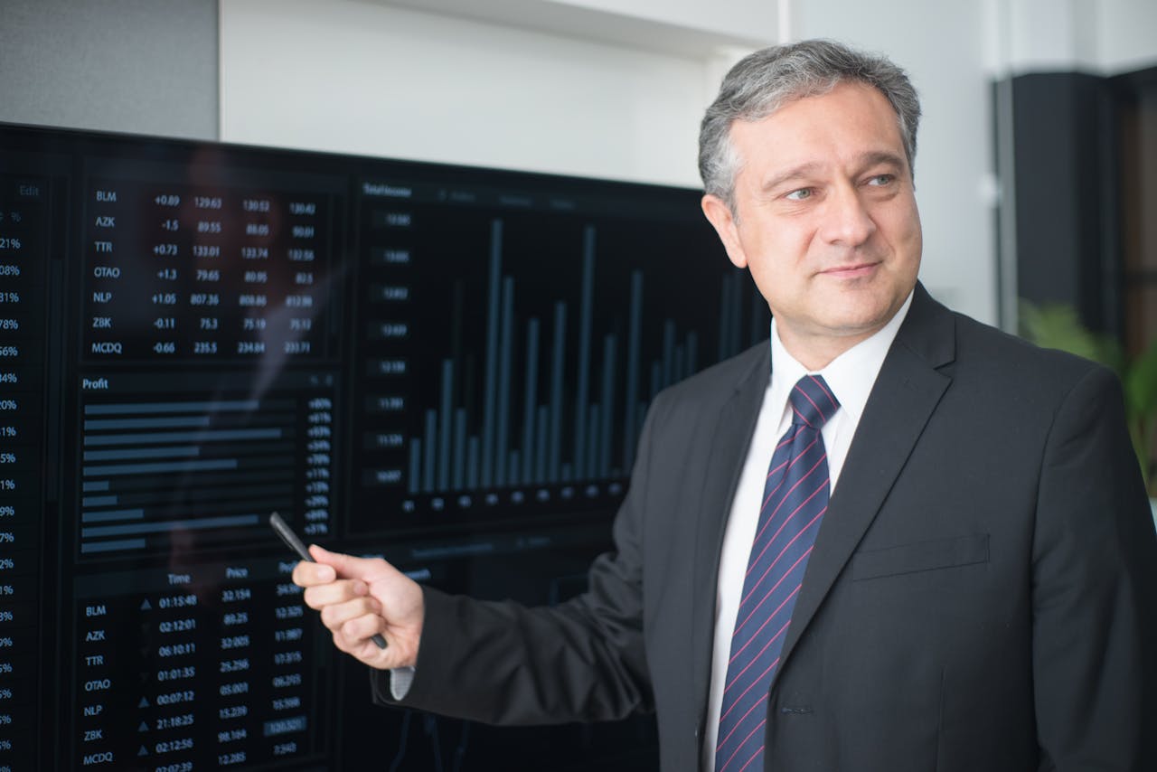 services-01 Professional man in suit reviewing financial charts on monitor, showcasing stock market trends.