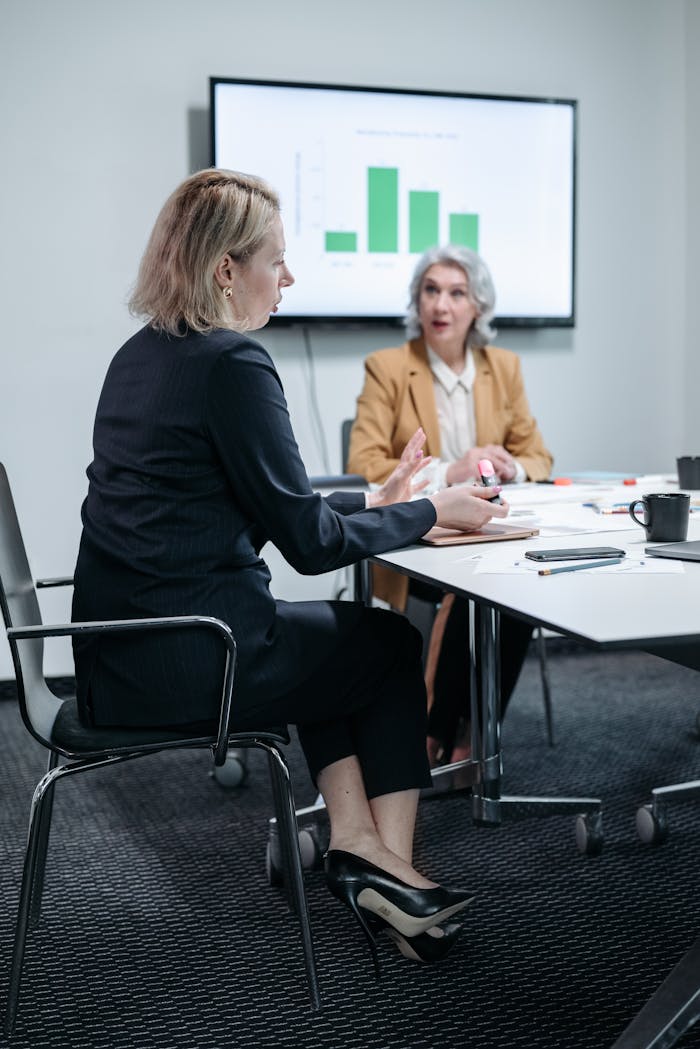 Camarero o chef: la pregunta que cambia tu forma de comprar Two professional women discussing a business strategy in a modern office setting.